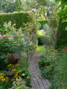Hecken, Rosenbögen, mäandernde Wege gliedern die Gartenräume und machen neugierig auf mehr im Landhausgarten Hantelmann
